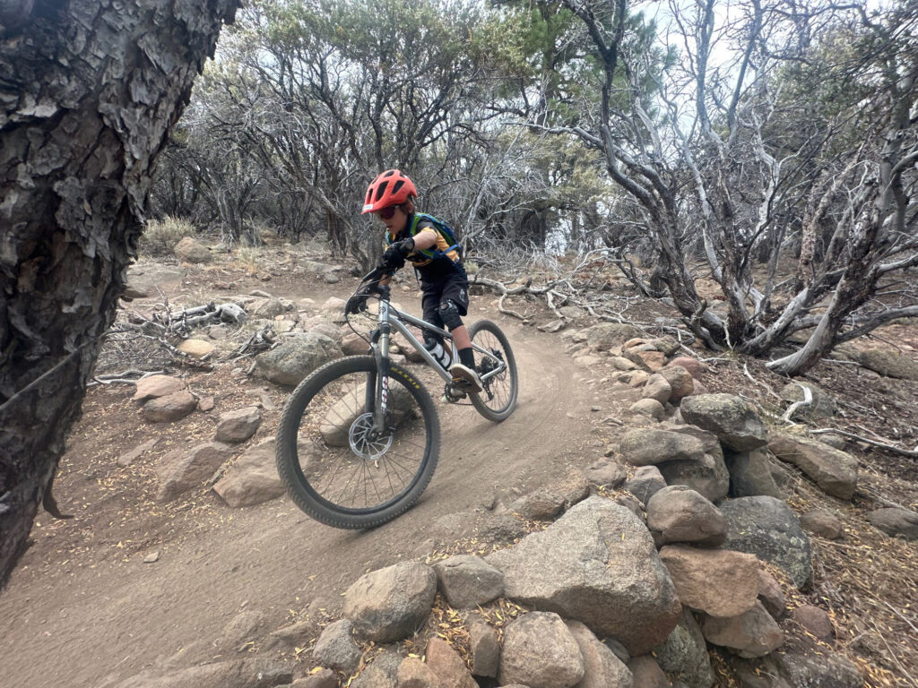 Young mountain biker riding singletrack trail through the Reno high desert at Silver State Senders summer camp